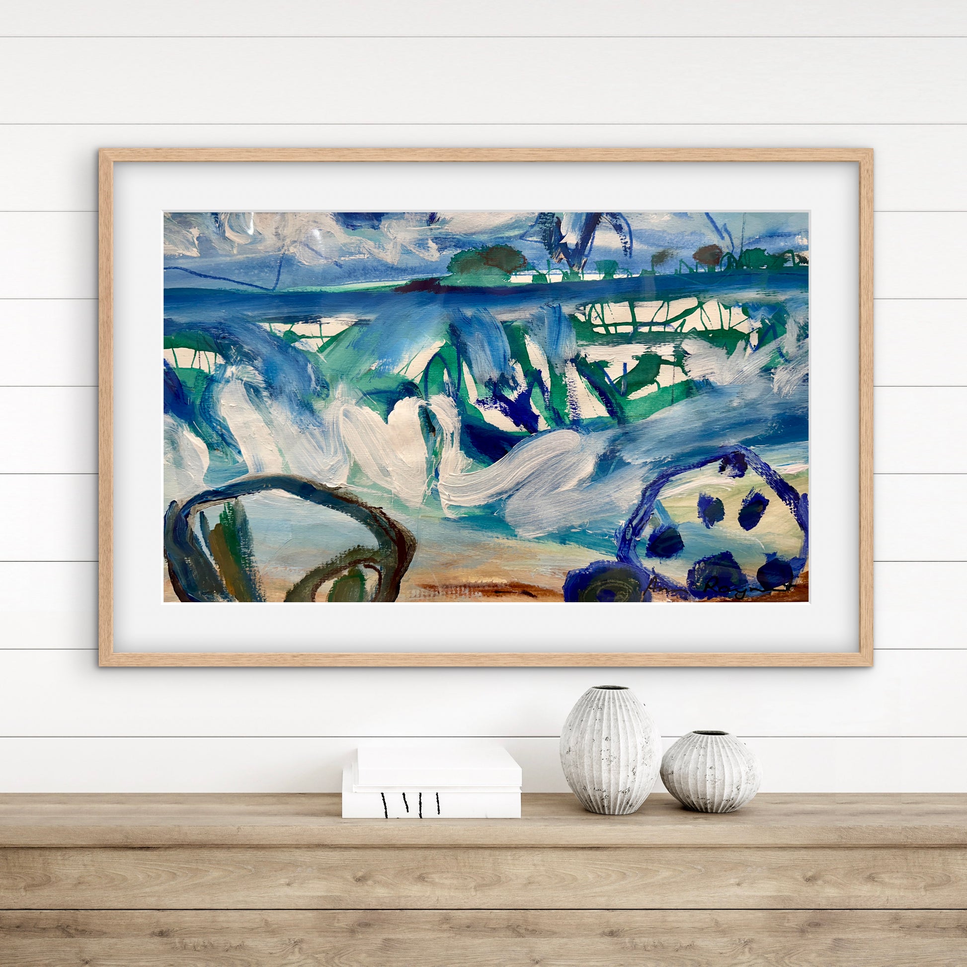 Framed abstract painting on a wall above a wooden shelf with decorative items.