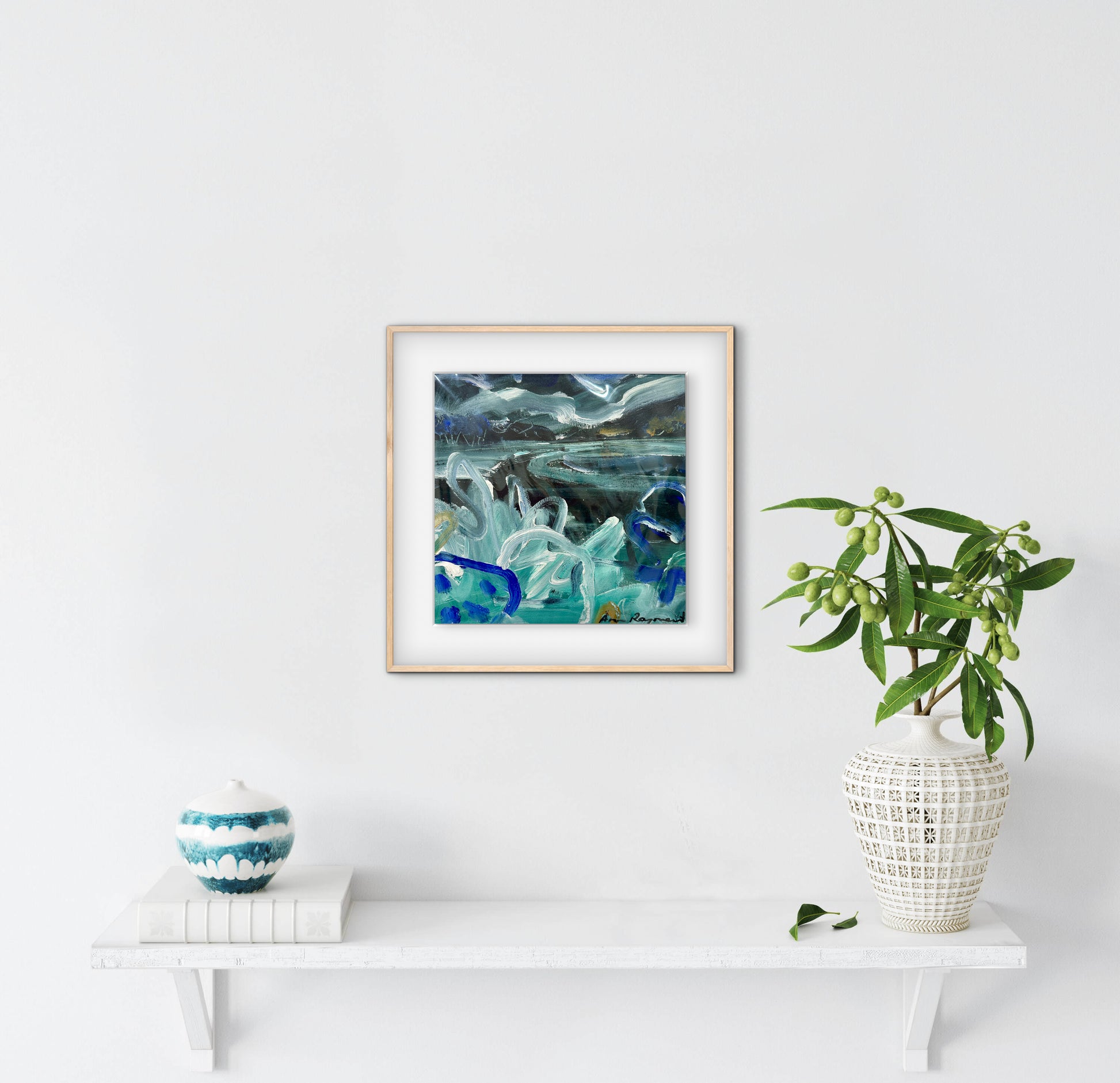 Framed abstract artwork on a white wall with decorative items below.