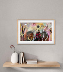Framed abstract artwork on a wall above a wooden shelf with books and a vase.